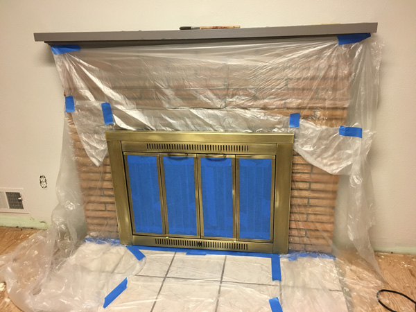 Preparing fireplace for paint with plastic.